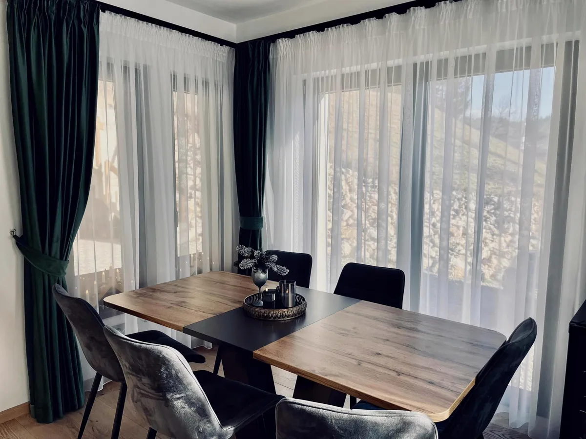 Sufragerie cu draperii verzi și vedere spre natură