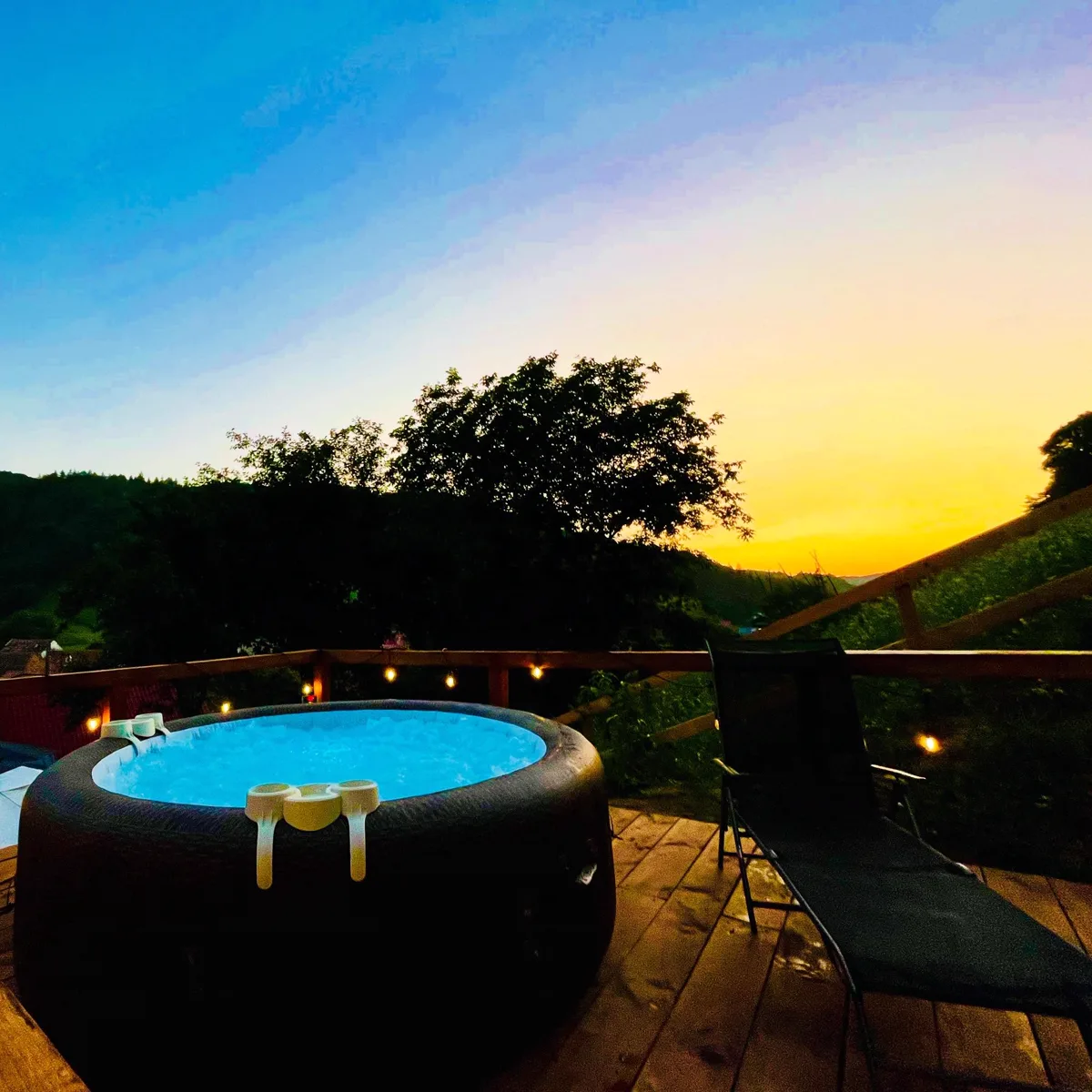Blue-lit hot tub at sunset with golden sky