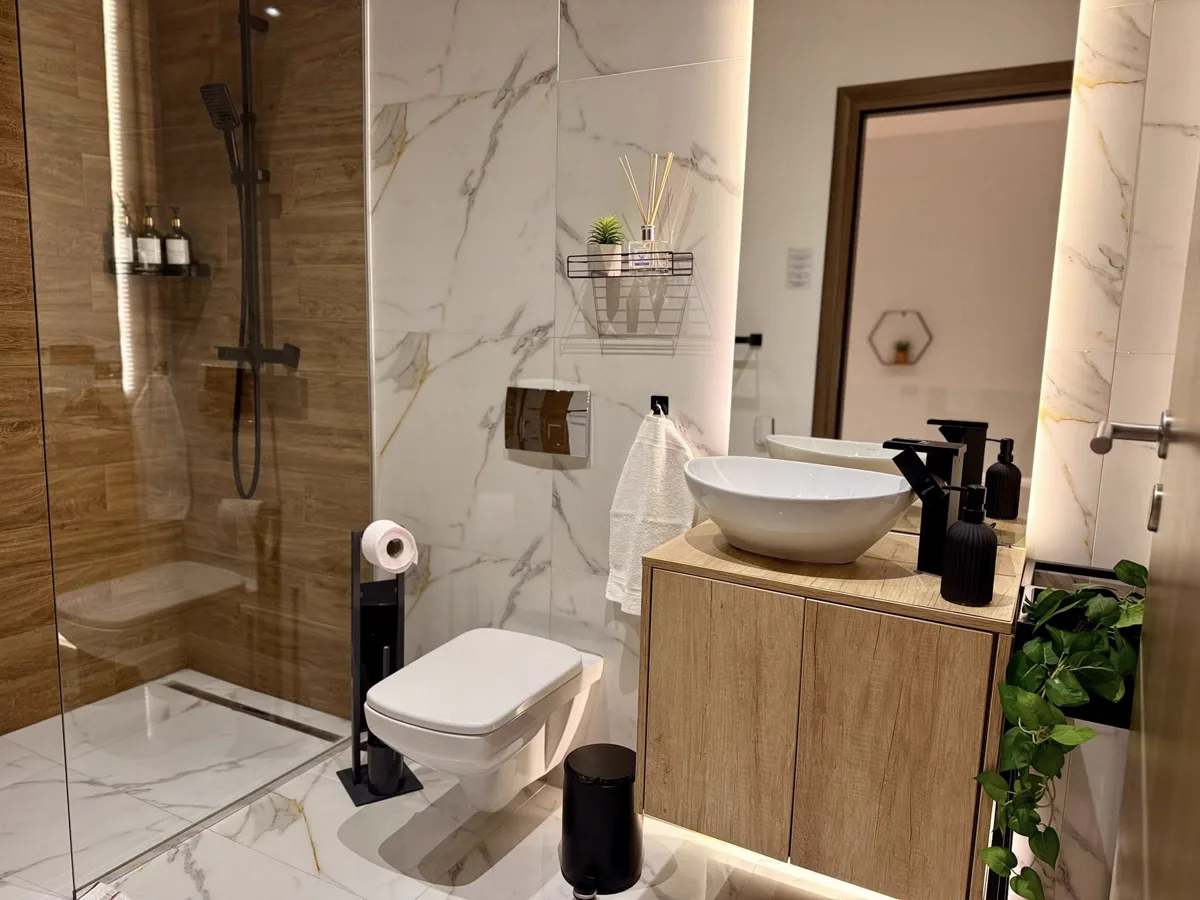 Bathroom with marble, wooden furniture and black taps